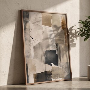 May include: A framed rectangular wall art piece featuring an abstract collage of layered paper textures in shades of beige, cream, charcoal grey, and black. The composition includes vertical line patterns, ink splatters, and torn edges.