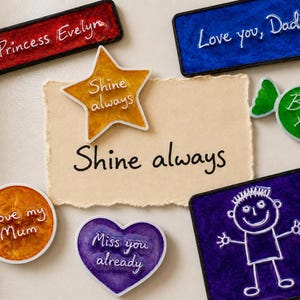 May include: A collection of colourful resin magnets in various shapes including a red rectangle with Princess Evelyn, a blue rectangle with Love you, Dad, a yellow star with Shine always, a green candy with Betsy XX, an orange circle with Love my Mum, a purple heart with Miss you already, and a purple square with a white stick figure drawing.