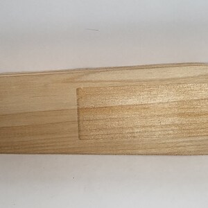 May include: A light-colored wooden serving tray with an oval shape and a rectangular recessed area. The tray is made of natural wood and has a smooth finish. The tray measures approximately 12 inches long.