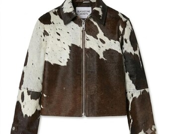 May include: A brown and white cowhide print jacket with a full-length silver metal zipper, a standard collar, and long sleeves with two silver snap buttons at each cuff. The interior label reads BLACKSTONE JACKETS in black text on a white background.
