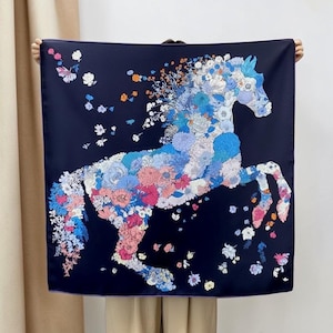 May include: A square scarf with a dark navy blue background featuring a large horse silhouette composed of various colorful flowers in shades of blue, pink, white, and orange, with additional scattered floral motifs surrounding the horse figure.