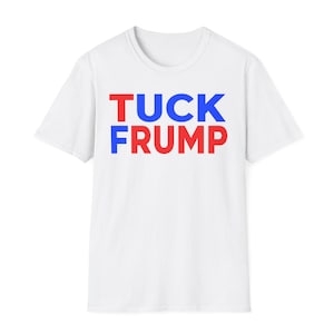 May include: White t-shirt with the words "TUCK FRUMP" printed in red and blue block letters. The text is centered on the front of the shirt. The shirt has a crew neck and short sleeves.
