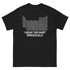 Puede incluir: Camiseta negra con una tabla periódica de elementos en blanco. El texto "I WEAR THIS SHIRT PERIODICALLY" está impreso debajo. Una camiseta con temática científica, ideal para los amantes de la química.