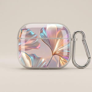 Op de afbeelding: Transparante beschermhoes voor draadloze oordopjes, met een parelmoer bloemenpatroon in roze, goud en blauw. Inclusief een zilveren karabijnhaak voor eenvoudige bevestiging aan een tas of sleutelhanger.
