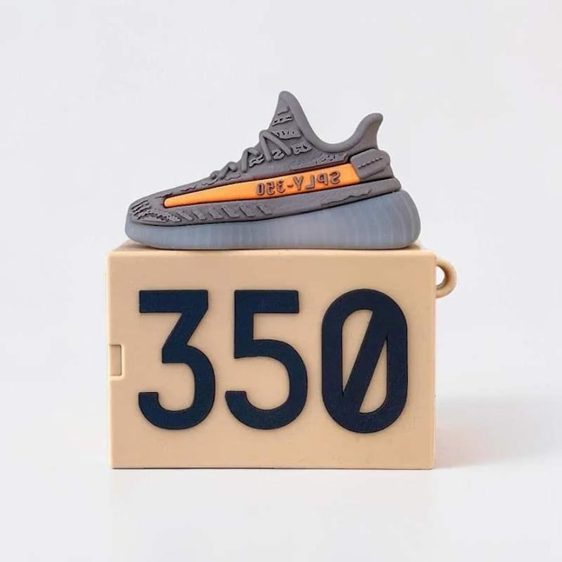 May include: A gray and orange sneaker-shaped case sits atop a tan box with the number "350" in dark blue. The sneaker has an orange stripe and the text "2B7A-YJ42". The case is likely for earbuds or small electronics.