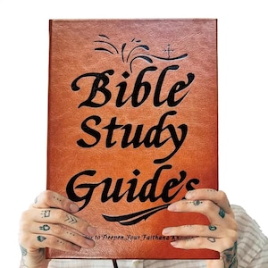 May include: A brown, textured, rectangular book cover with black embossed text that reads Bible Study Guide's to Deepen Your Faith and Knowledge. The cover features a decorative flourish above the title and a cross symbol above the letter i.