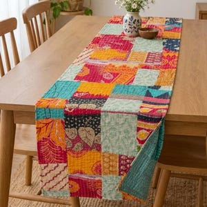 May include: A rectangular table runner featuring a patchwork design of various fabric squares in vibrant shades of red, yellow, orange, teal, and blue. The textile displays intricate kantha-style stitching throughout and a multi-patterned surface.