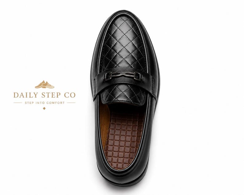May include: A black loafer with a quilted diamond pattern on the vamp and a metallic bit across the bridge. The interior features a brown grid-textured insole. The text DAILY STEP CO STEP INTO COMFORT is visible to the left of the shoe.