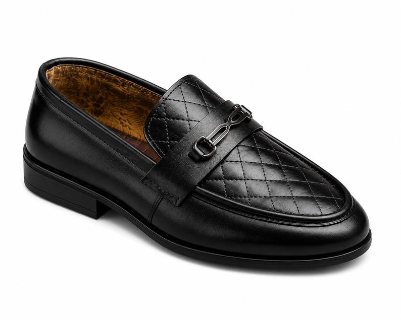 May include: A black loafer shoe featuring a quilted diamond pattern on the vamp, a smooth leather finish on the sides, and a dark metallic horsebit hardware detail across the top. The interior lining is a textured, mottled brown material.