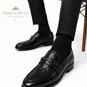 May include: Black leather loafers featuring a quilted diamond pattern on the vamp, a dark metal horsebit detail across the bridge, and a low heel. The text DAILY STEP CO STEP INTO COMFORT is visible in the upper left corner of the image.
