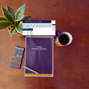 Pode incluir: Uma vista de cima de um espaço de trabalho com uma planta, um smartphone exibindo um gráfico de negociação, um Forex Trading Journal, uma caneta, uma caneca de café e um painel de estatísticas de desempenho. O diário é azul escuro com o texto "FOREX TRADING JOURNAL".