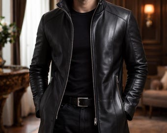 May include: A black leather jacket with a zip-up front and a high collar. The jacket is long, reaching to the mid-thigh, and is worn with a black shirt and black pants. The image is set in a room with a chandelier.