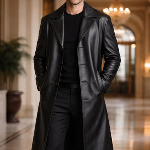 May include: A black leather trench coat with a classic design. The coat features a notched collar, button closure, and pockets. The long coat is worn over a black outfit. The image also includes a logo of a goat with a crown.