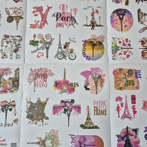 May include: Sheet of stickers featuring various designs with a Parisian theme. The stickers include images of the Eiffel Tower, bicycles, hot air balloons, and the word "Paris" in different fonts and styles. The color palette is primarily pink and white.