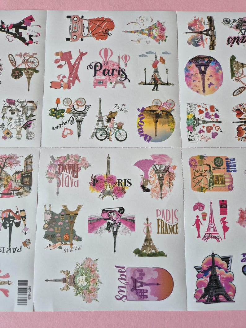 May include: Sheet of stickers featuring various designs with a Parisian theme. The stickers include images of the Eiffel Tower, bicycles, hot air balloons, and the word "Paris" in different fonts and styles. The color palette is primarily pink and white.