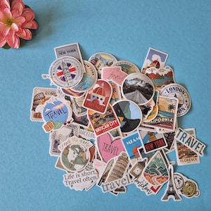 May include: A collection of travel-themed stickers with various designs, including landmarks like the Eiffel Tower and Big Ben, and the text "TRAVEL". The stickers are in various shapes and sizes, with a pink flower in the upper left corner.