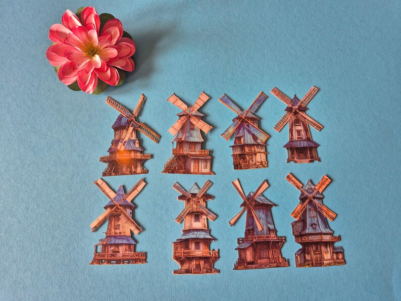 May include: A collection of paper windmills with detailed architectural designs, featuring brown, blue, and orange hues. A pink and red flower with a yellow center is positioned at the top left corner against a light blue background.