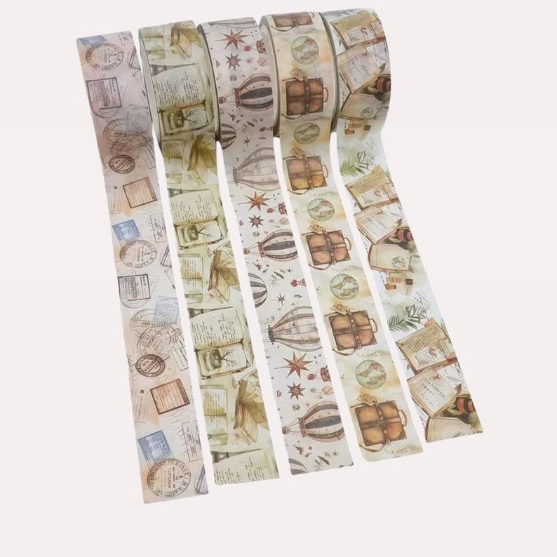 Puede incluir: Cinco rollos de cinta adhesiva decorativa con dise&ntilde;os de inspiraci&oacute;n vintage. Los patrones incluyen globos aerost&aacute;ticos marrones, estrellas, libros abiertos, sellos de viaje y maletas en tonos beige, marr&oacute;n y azul claro sobre fondo claro.