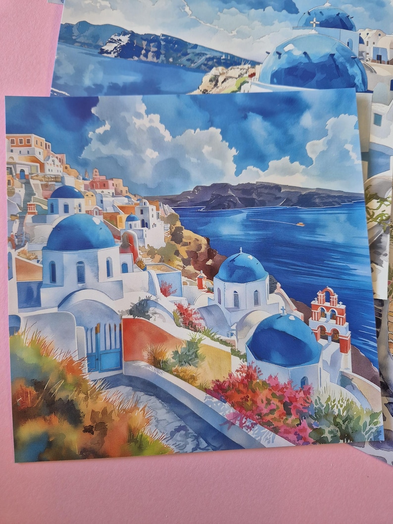 May include: Watercolour print depicting a Greek village with white buildings, blue domes, and the Aegean Sea. The artwork uses vibrant blues, reds, and oranges, with a cloudy sky. The print captures the essence of a coastal town.