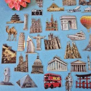 May include: A selection of travel-themed stickers depicting famous landmarks such as the Eiffel Tower, the Statue of Liberty, and a red double-decker bus. Other stickers include a camera, a camel, and a yellow taxi. A pink flower is in the upper left corner.