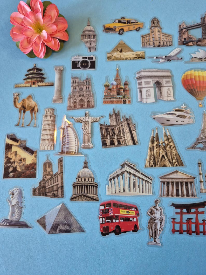 May include: A selection of travel-themed stickers depicting famous landmarks such as the Eiffel Tower, the Statue of Liberty, and a red double-decker bus. Other stickers include a camera, a camel, and a yellow taxi. A pink flower is in the upper left corner.