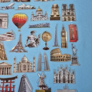 May include: A selection of travel-themed stickers depicting famous landmarks. Includes the Tower Bridge, the Eiffel Tower, Big Ben, the Colosseum, and the Taj Mahal. The stickers are set against a light blue backdrop.