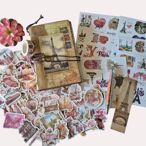 Peut inclure: Ensemble de papeterie sur le th&egrave;me de Paris. Comprend un journal, des autocollants, du ruban adh&eacute;sif washi et un stylo. Les autocollants pr&eacute;sentent des images de la Tour Eiffel, de fleurs et d'autres motifs parisiens. Une fleur rose est &eacute;galement incluse.