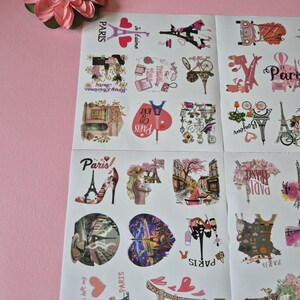 May include: Sheets of Paris-themed stickers with various illustrations, including the Eiffel Tower, hearts, and fashion elements. The stickers feature text like "Paris," "Je t'aime," and "Bonjour," with a pink flower in the corner.