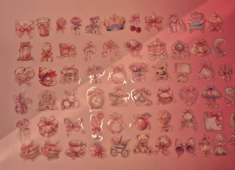 May include: A collection of small, pink-toned decorative stickers featuring various illustrations including bows, animals, flowers, sweets, clocks, and household items arranged in a grid pattern on a light pink background.