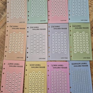 Pode incluir: Um conjunto de rastreadores de desafios de poupan&ccedil;a coloridos. Cada rastreador apresenta um design de favo de mel com valores de 1&euro; a 100&euro;, e o texto "Savings Challenge Tracker". Os rastreadores s&atilde;o de v&aacute;rias cores, com o valor total poupado impresso.
