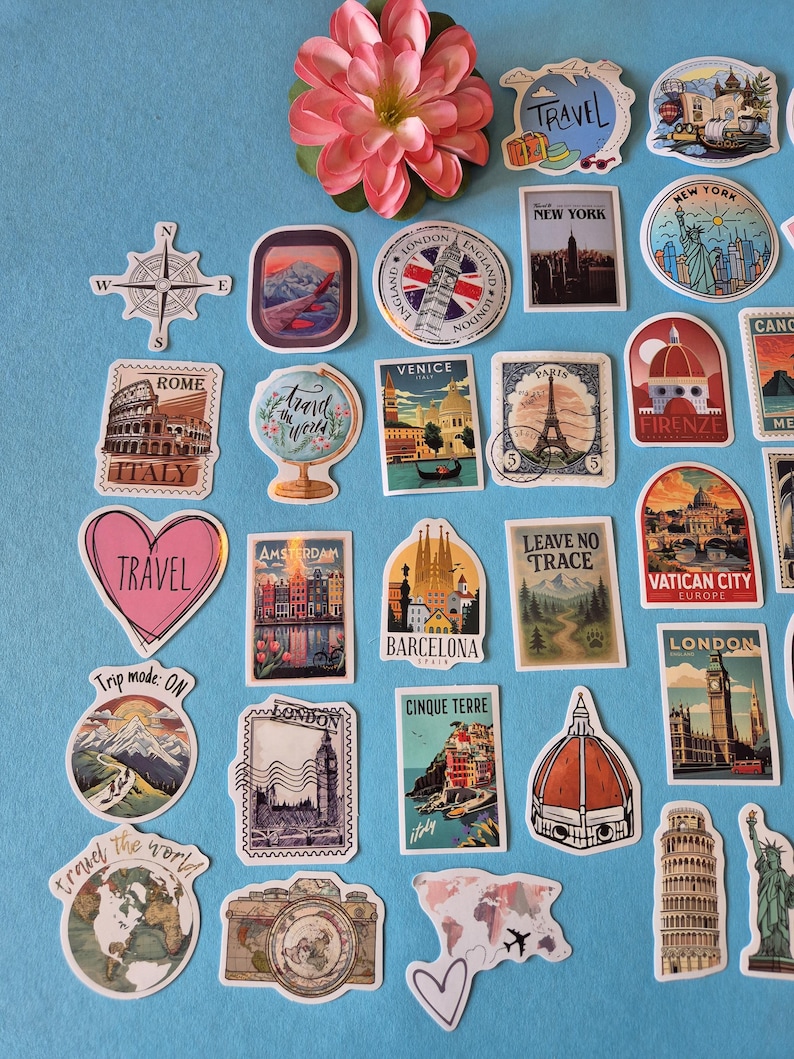 May include: A collection of travel-themed stickers featuring landmarks like the Eiffel Tower, the Statue of Liberty, and the Colosseum. The stickers are in various shapes and sizes, with a compass rose and a pink flower on a blue background.