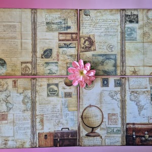 Op de afbeelding: Een collage van vier papieren panelen in vintage-stijl met een roze bloem. De panelen bevatten antieke kaarten, postzegels, handgeschreven tekst en illustraties van globes en reisgerelateerde afbeeldingen. Twee kleine bruine koffers zijn zichtbaar.