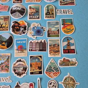May include: A collection of travel-themed stickers featuring landmarks and destinations like the Eiffel Tower, the Statue of Liberty, and the Golden Gate Bridge. The stickers showcase various cities and countries, including London, Paris, and Italy.