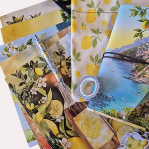 Op de afbeelding: Een verzameling briefpapier met een citroenthema. Inclusief een pen, ansichtkaarten, een notitieboek, stickers, een etui en decoratieve tape. De items bevatten illustraties van citroenen, bloemen en kustlandschappen, met een kleurenpalet van geel, groen en blauw.