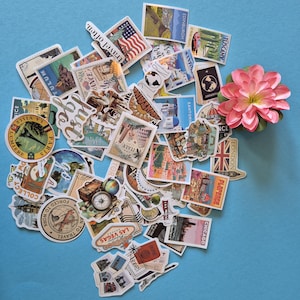 Puede incluir: Una colecci&oacute;n de pegatinas con tem&aacute;tica de viajes con im&aacute;genes de monumentos y banderas. Las pegatinas incluyen la Torre Eiffel, la bandera estadounidense y el London Eye. Tambi&eacute;n hay una flor rosa.