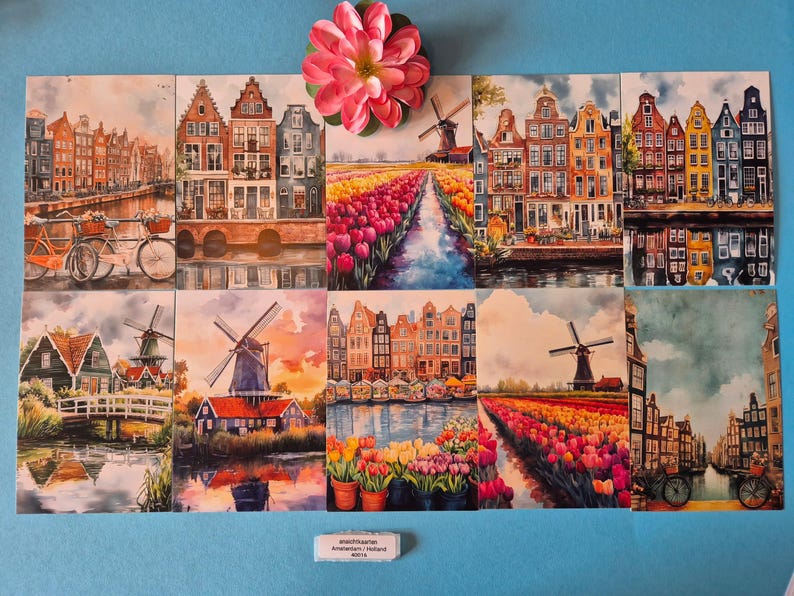 Op de afbeelding: Een verzameling aquarelprints met Nederlandse landschappen. De prints tonen grachten, windmolens en kleurrijke tulpenvelden. Een roze bloem ligt bovenop de prints. De tekst onderaan luidt "schoonbaarn Amsterdam / Holland 40/12".