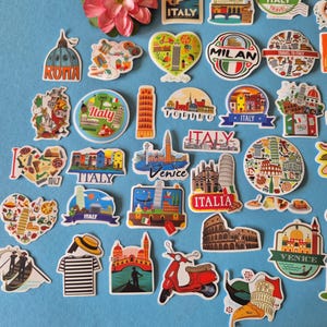 May include: A collection of colorful Italy-themed stickers featuring landmarks like the Leaning Tower of Pisa, the Colosseum, and gondolas. Some stickers have text like "Italy", "Rome", "Venice", and "Florence". A pink flower is also present.