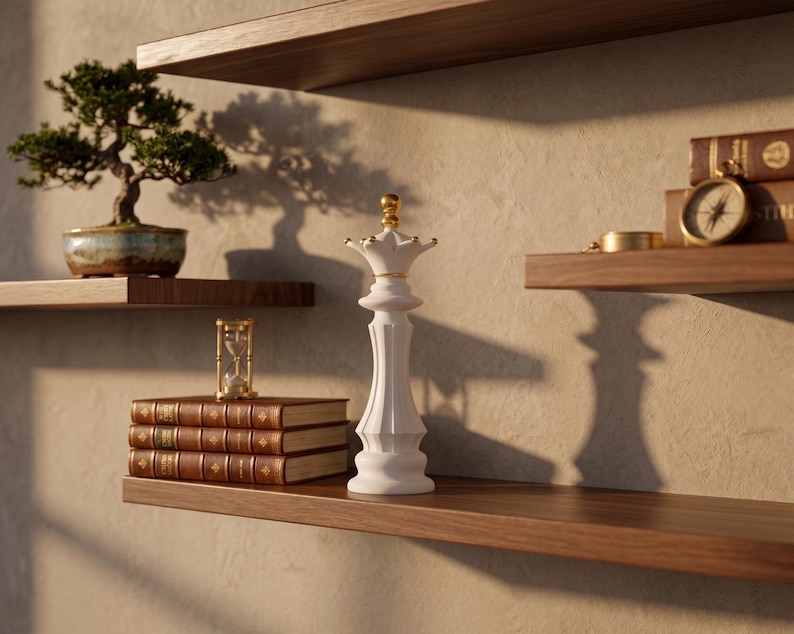 May include: A decorative display featuring a bonsai tree in a blue and brown pot, a white chess piece, a stack of books, a compass, and an hourglass. The items are arranged on wooden shelves against a textured wall, creating a serene and elegant aesthetic.