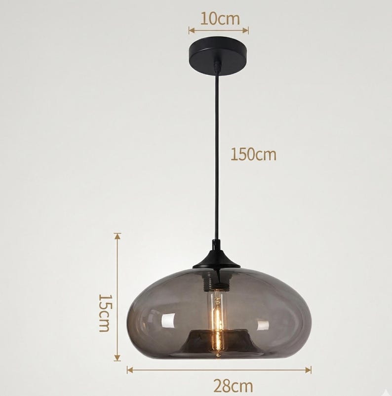 Op de afbeelding: Een moderne hanglamp met een rookglazen kap. De lamp wordt opgehangen aan een zwart snoer, met een totale lengte van 150 cm. De kap is 28 cm breed en 15 cm hoog. De plafondbevestiging heeft een diameter van 10 cm.