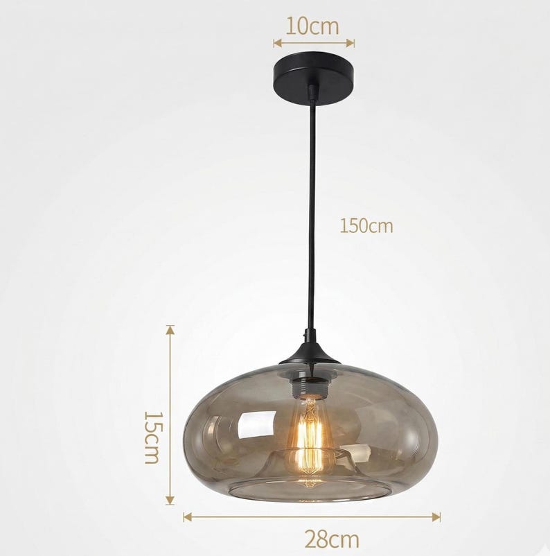 Op de afbeelding: Een moderne hanglamp met een rookglazen kap, 28 cm breed en 15 cm hoog. De zwarte armatuur hangt aan een snoer van 150 cm en heeft een plafondbevestiging van 10 cm. De gloeilamp is zichtbaar in de glazen kap.