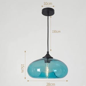Op de afbeelding: Een moderne hanglamp met een turquoise glazen kap, 28 cm breed en 15 cm hoog. De lamp heeft een zwarte plafondbevestiging, een zwart snoer en een zwarte basis. De totale lengte van de lamp is 150 cm.