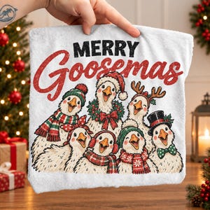 Könnte beinhalten: Ein weißes Handtuch mit einer Grafik von sechs Gänsen, die festliche Accessoires wie Weihnachtsmützen, Schals, Ohrenschützer, ein Rentiergeweih-Stirnband und einen Zylinder mit Fliege tragen, sowie dem Schriftzug MERRY Goosemas in Schwarz und Rot.