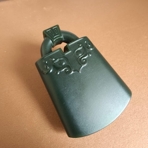 May include: Dark green jade pendant with a curved rectangular shape and decorative carvings. The pendant has a loop at the top for hanging. The jade has a smooth, polished surface.
