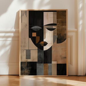 Könnte beinhalten: Abstrakter Kunstdruck in einem Holzrahmen, der ein geometrisches Gesicht darstellt. Das Kunstwerk verwendet Schwarz-, Beige- und Brauntöne. Das Gesicht besteht aus geometrischen Formen und schafft eine moderne und künstlerische Ästhetik.