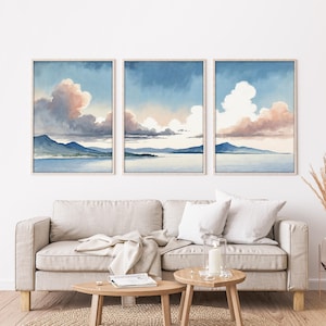 Peut inclure: Trois impressions encadrées de paysages à l'aquarelle. Chacune présente une scène sereine d'un lac bleu, de montagnes et d'un ciel rempli de nuages duveteux dans des tons de rose, pêche et bleu. Les cadres sont de couleur bois clair.