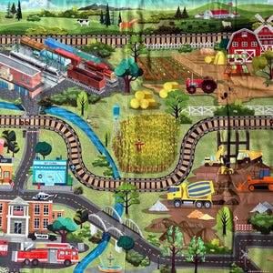 May include: A colorful play mat featuring a town and farm scene with roads, train tracks, and buildings. The mat includes a train station, bakery, vet clinic, fire station, and farm with a red barn and tractor. The design is vibrant and detailed.