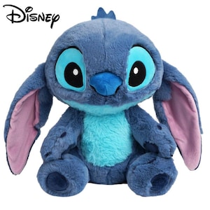 May include: A plush toy of the character Stitch from Disney, featuring dark blue fur, a light blue chest patch, large ears with pink inner lining, and oversized eyes with black pupils. The word Disney is printed in black in the top left corner.