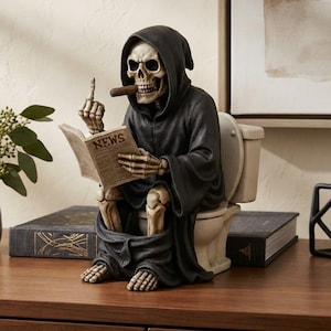 May include: A decorative figurine of a skeleton wearing a black hooded robe, sitting on a white toilet. The skeleton holds a newspaper with the word NEWS printed on the cover and a brown cigar in its mouth, while gesturing with one finger.