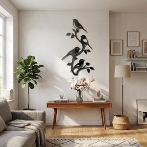 May include: Black metal wall art featuring four birds perched on branches. The birds and branches are intricately cut, creating a decorative silhouette. The artwork is mounted on a white wall, adding a touch of nature-inspired decor to the room.