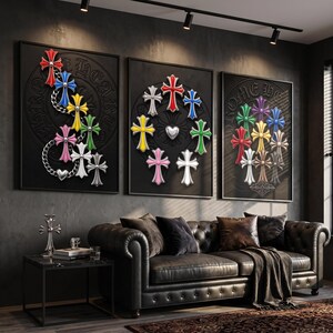 May include: Three framed wall art pieces featuring collections of colourful, embossed cross emblems on black backgrounds. The left panel shows crosses linked by chains, the centre features a circular arrangement with a heart, and the right displays a cluster.